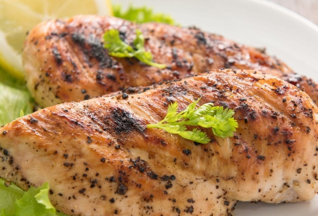 air fryer chicken breasts on a board topped with a sprig of parsley for garnish