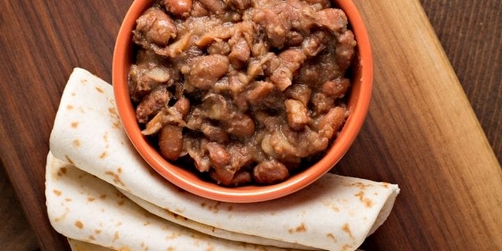 bowl of beans and rolled up tortillas on the side