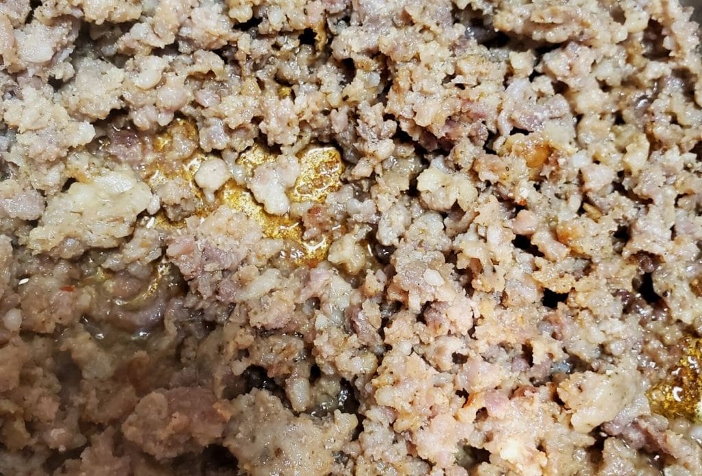 blue and gold sausage browning in a pan for rotel dip