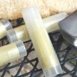 Bug bites sticks and salve tins laying on a table with some luffa