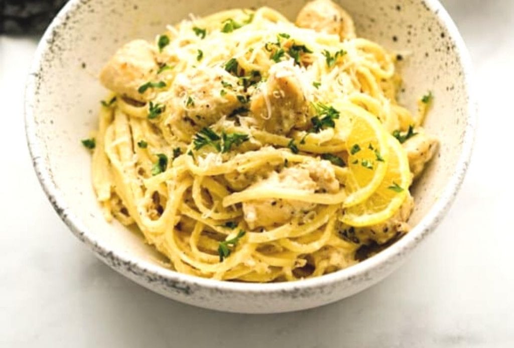 creamy lemon and chicken pasta piled up in a white bowl and garnished with parsley