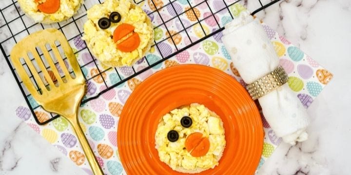 easter chick toast on a plate next to a tray full of them with a gold spatula and a roll of silverware