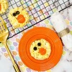 easter chick toast on a plate with silverware and a gold spatula and a tray full of easter chick toast nearby