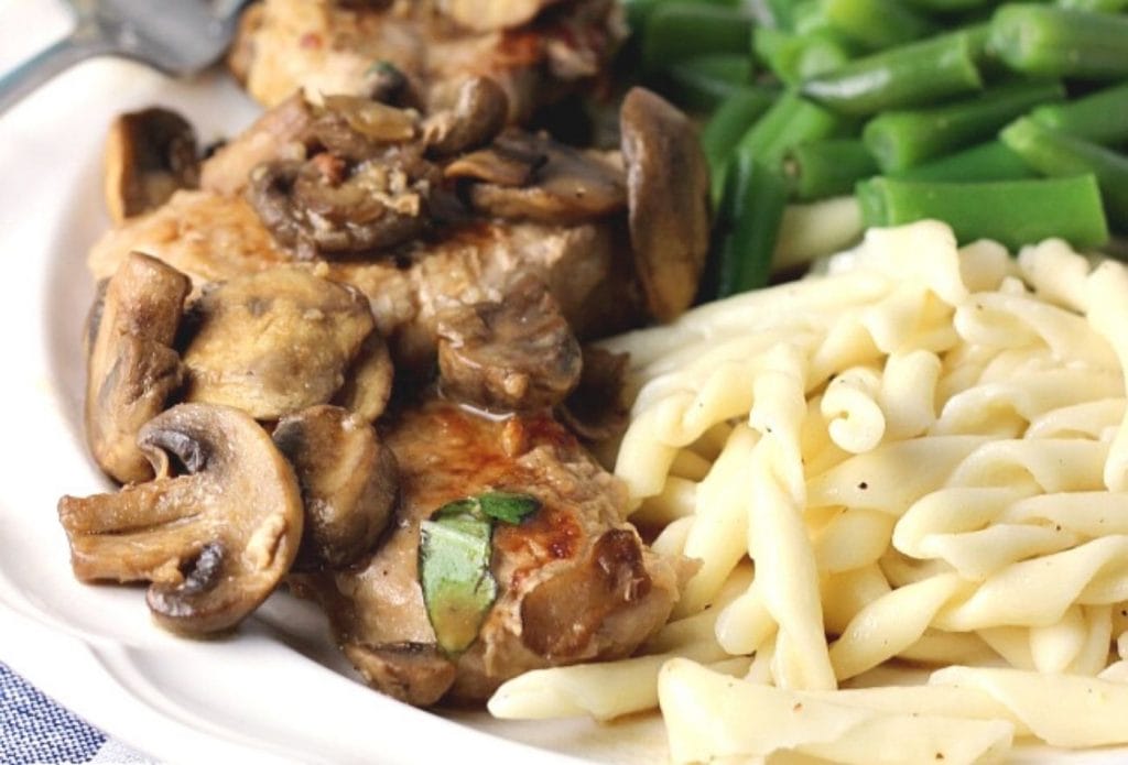 pork tnderloin marsala on a plate with green beans and twisty pasta