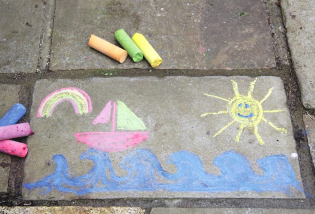 bright sticks of homemade chalk and a drawing on the sidewalk for an easy art project for kids in daycare