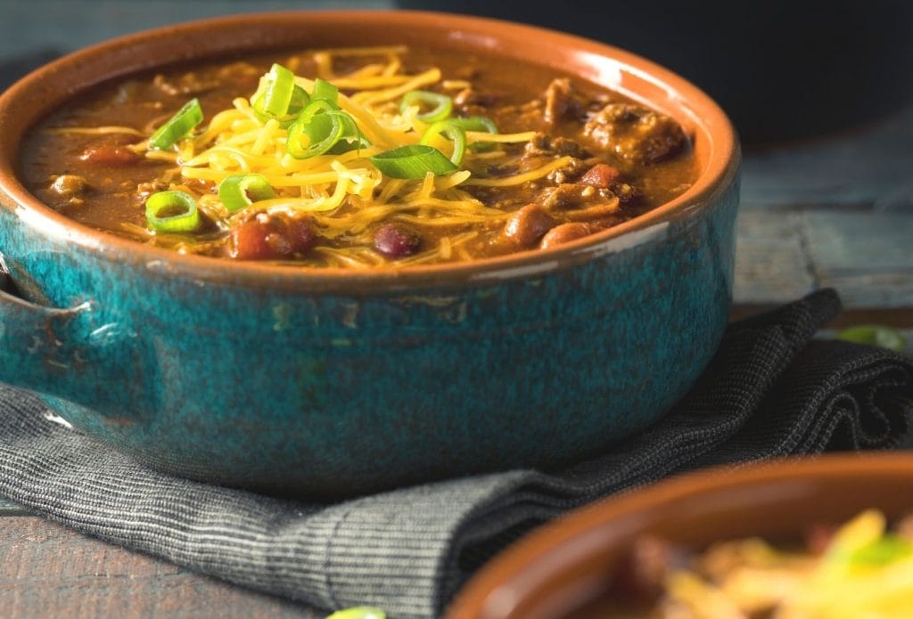 rotel chili topped with cheese and onions on a grey towel
