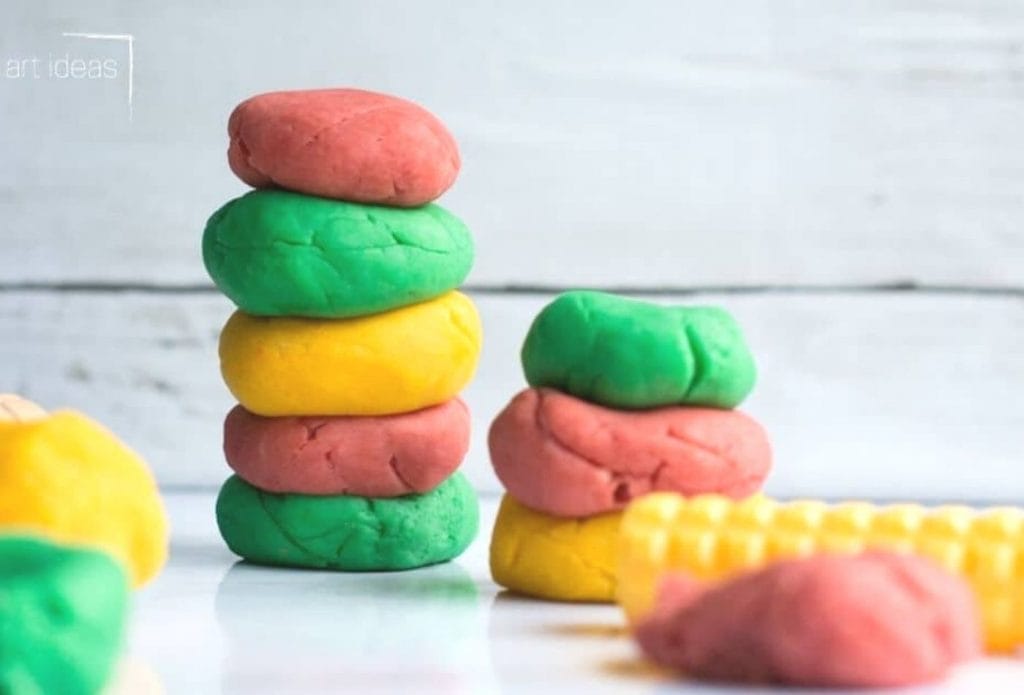 homemade crockpot playdough in piles stacked up on a board with rolling pins