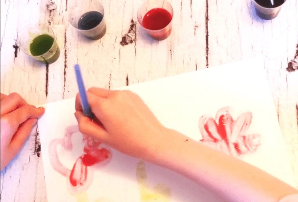 homemade paint made from nature in small cups with a child painting a painting with a brush