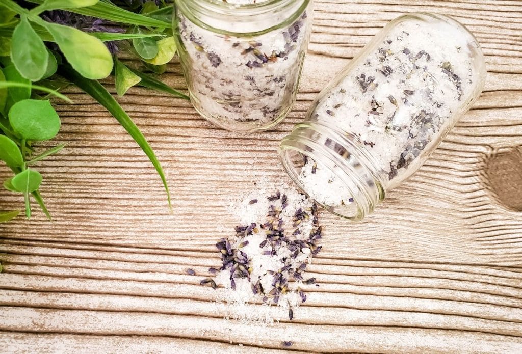 lavender bath salts in jars, one spilling out and one sitting up