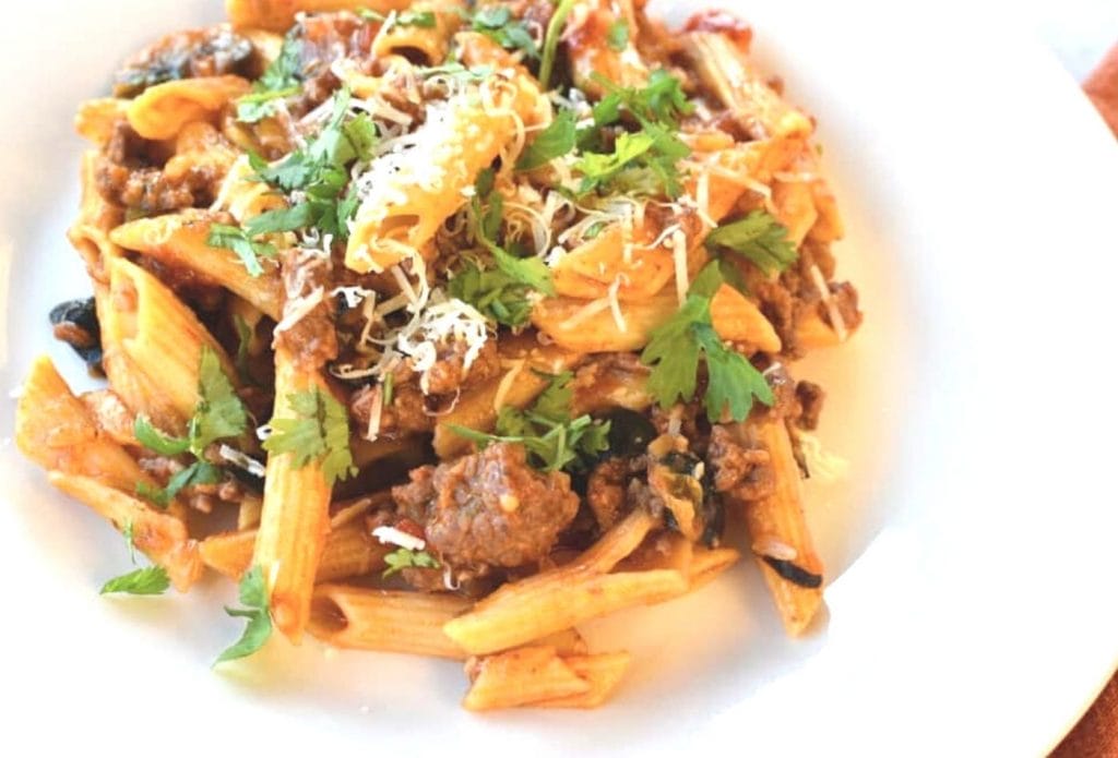 one pot taco pasta in a bowl garnished with sprinkles of cheese and chopped parsley