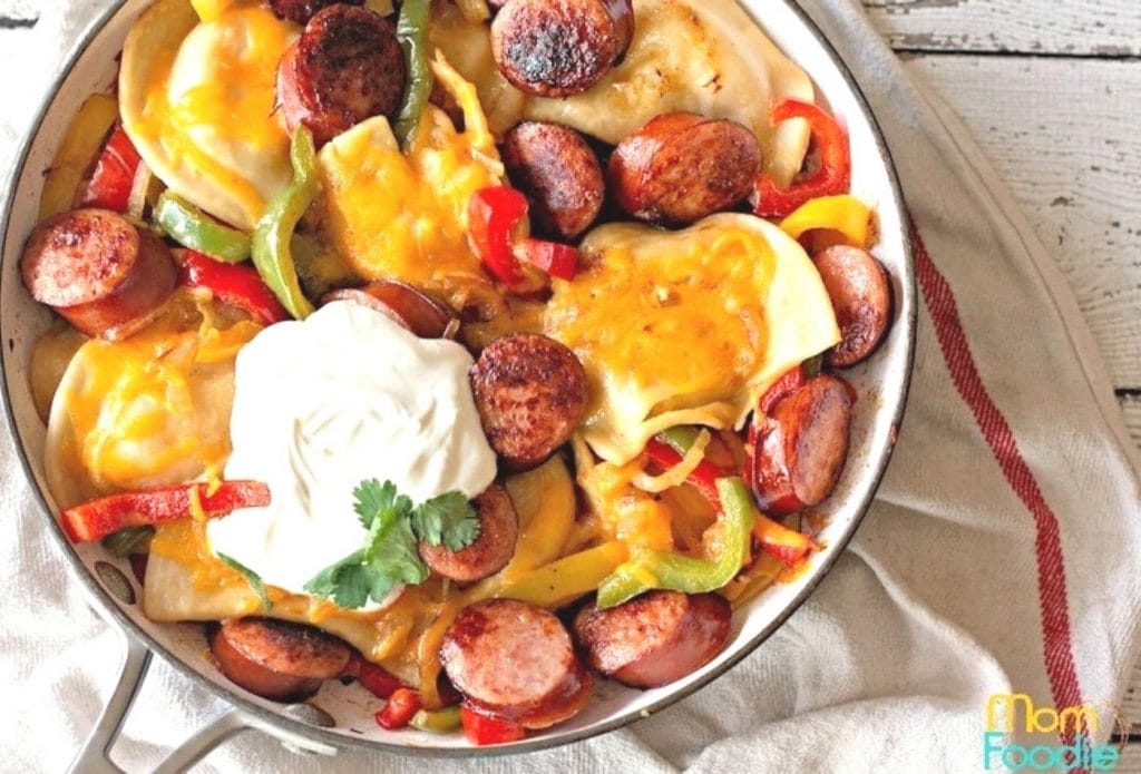 perogies and kielbasa in a skillet by a tea towel