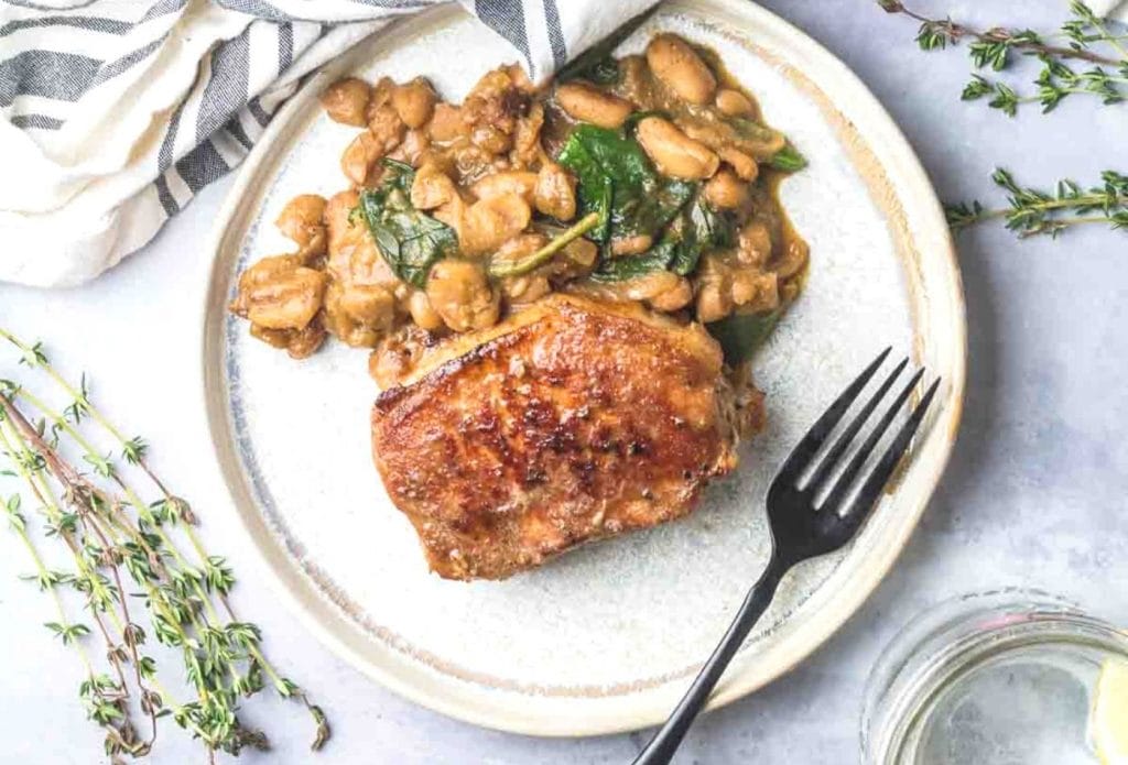Pork chop and spinach skillet dinner on a plate with a fork