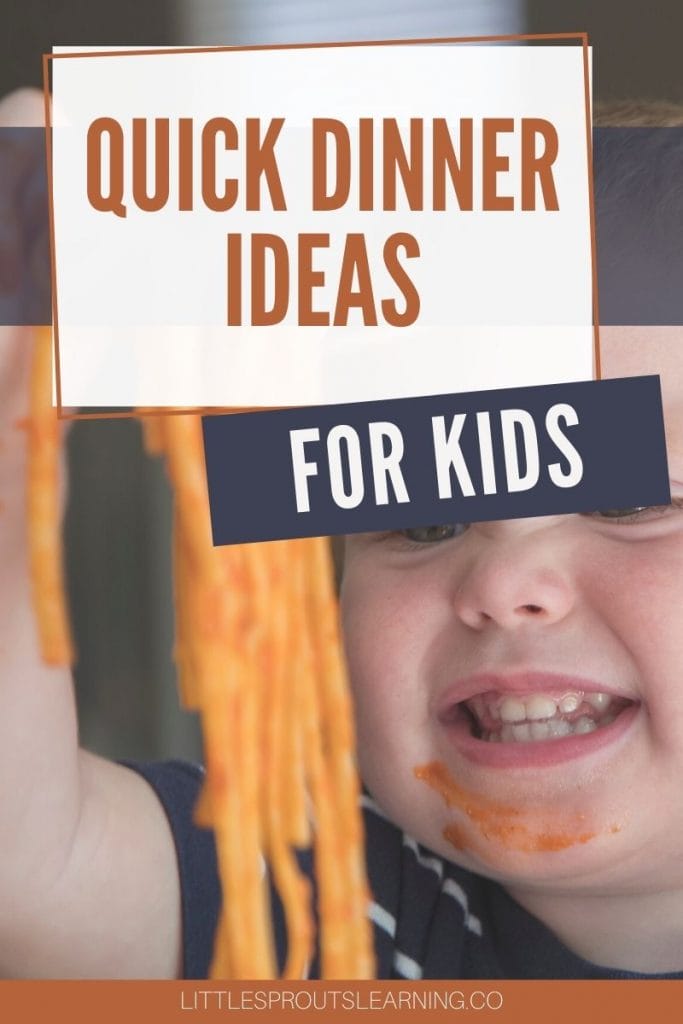 child lifting up a fork full of spaghetti to eat it and smiling with a smudge of spaghetti sauce on his face