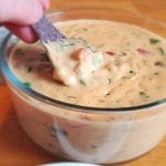 Rotel dip with real cheese in a bowl with a chip dipping in for a bite