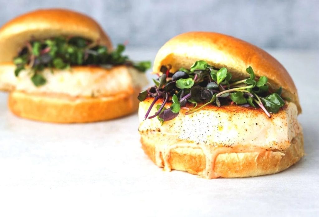 spicy halibut burgers on buns with microgreens and sauce