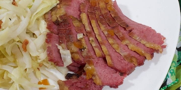sliced corned beef from the slow cooker on a plate with some irish cabbage