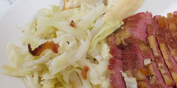 Traditional irish cabbage with bacon on a plate with slices of corned beef and crusty bread