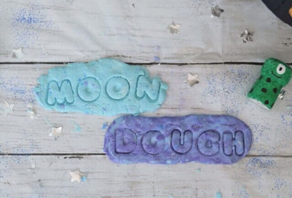 blue and purple moon dough pressed on a board with the words moon and dough pressed in with cutters
