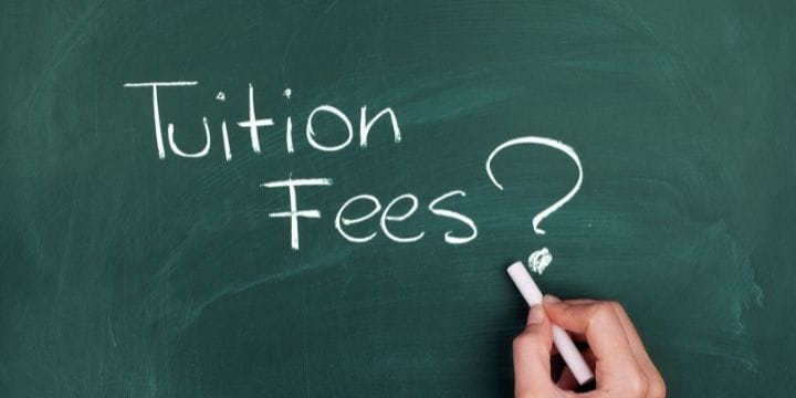 chalk board with tuition fees? written on it and a hand with chalk