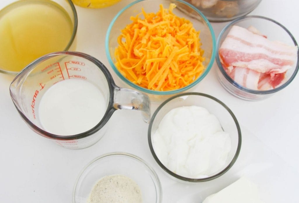ingredients for crack chicken on a board, milk, sour cream, cheese, bacon, etc.