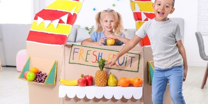 kids playing grocery store with pretend fruits and vegetables and a check out station