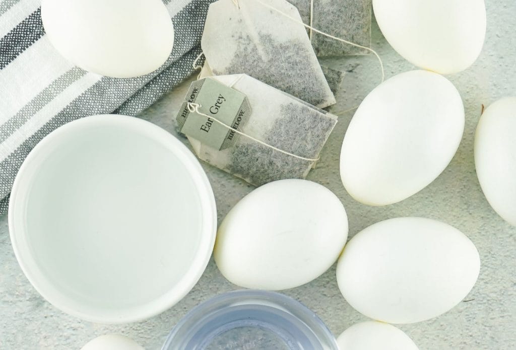 white eggs, bowls of clear liquid, and tea bags on a table