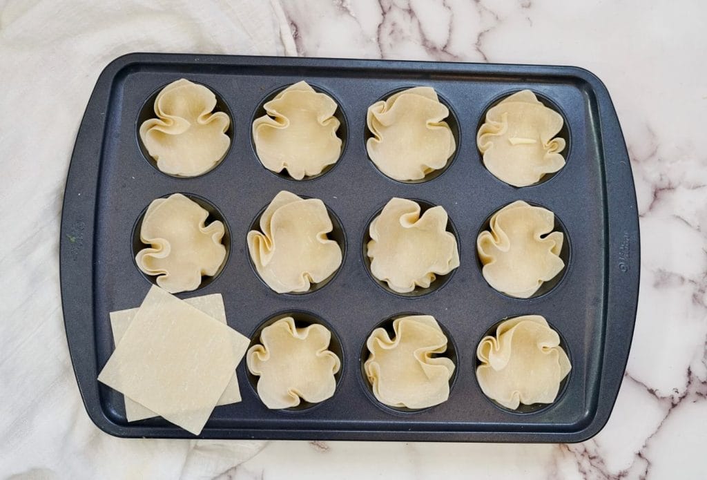 wonton wrappers pressed into muffin tin for pizza cups