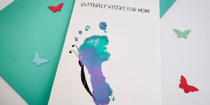 butterfly kisses for mom mother's day card on a table with a piece of teal paper and paper butterflies sprinkled around