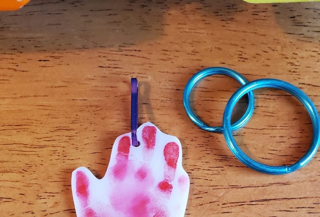 hand print shrinky dink keychain made with stamp pad and two rings next to it