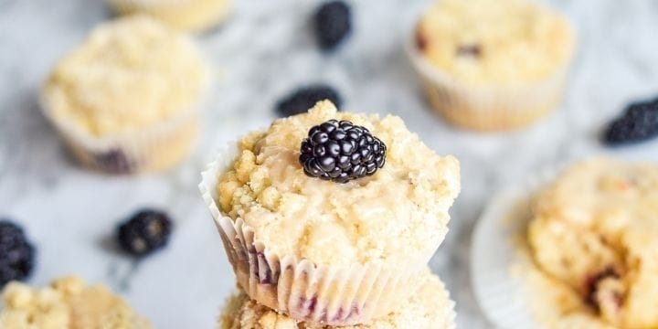 blackberry lemon crumb muffins in a stack with a blackberry on top