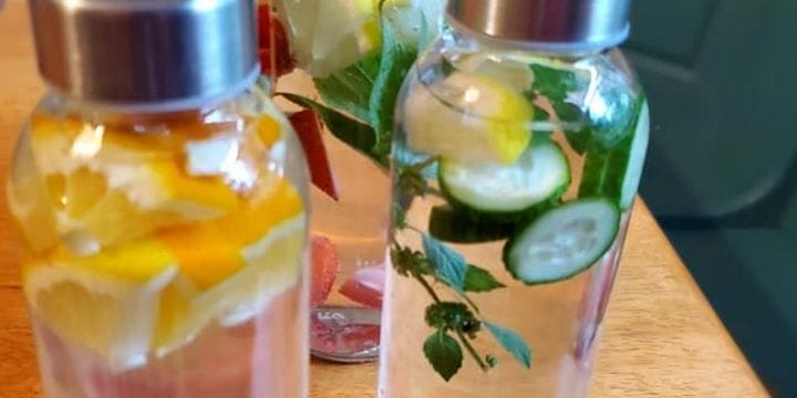 cucumber mint infused water bottles with lemon on the table with other infused waters