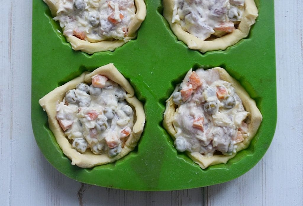 mini chicken pot pies in a muffin pan ready to bake