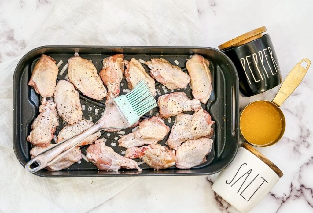chicken wings on a pan with a pastry brush and some butter
