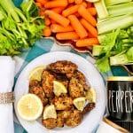 air fryer chicken wings on a plate with lemons and fresh carrots and celery
