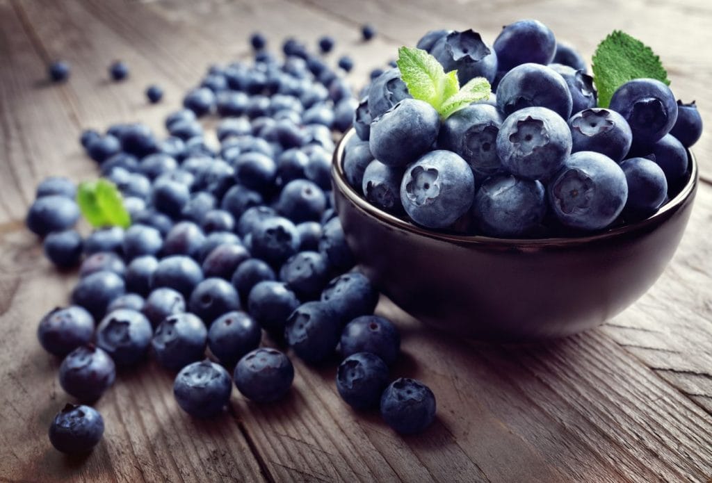 blueberries in a bowl with blueberries on the counter