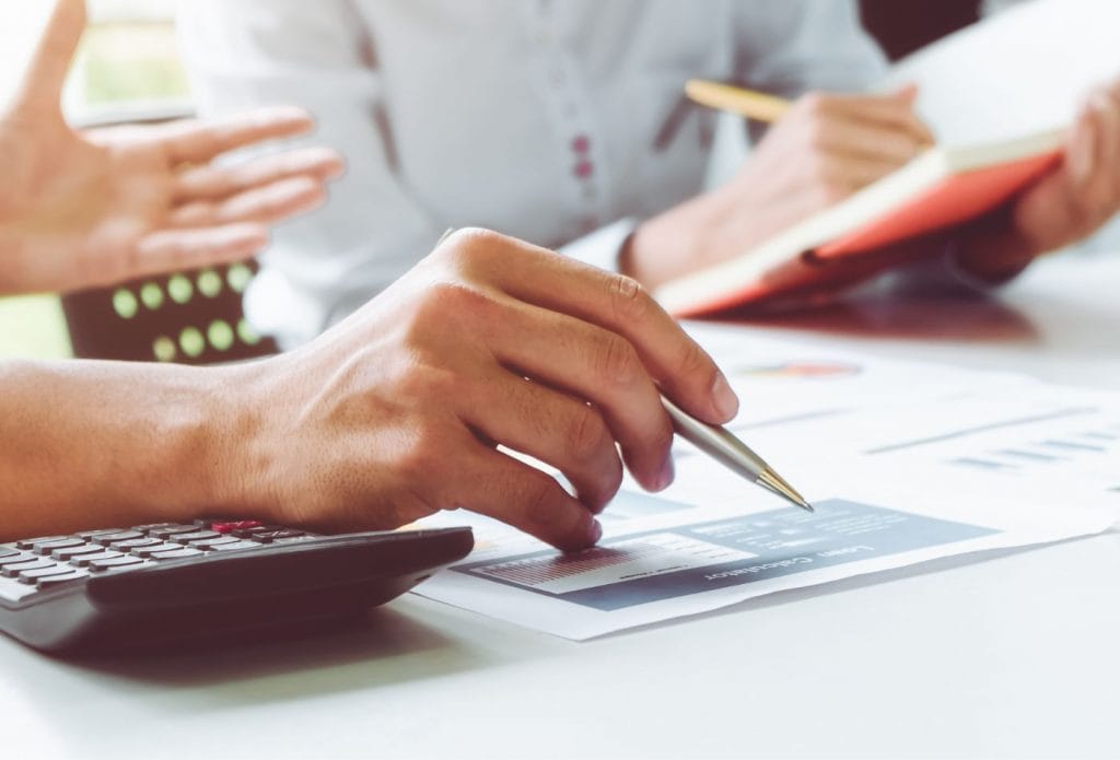 business people pointing to tax paperwork at a table