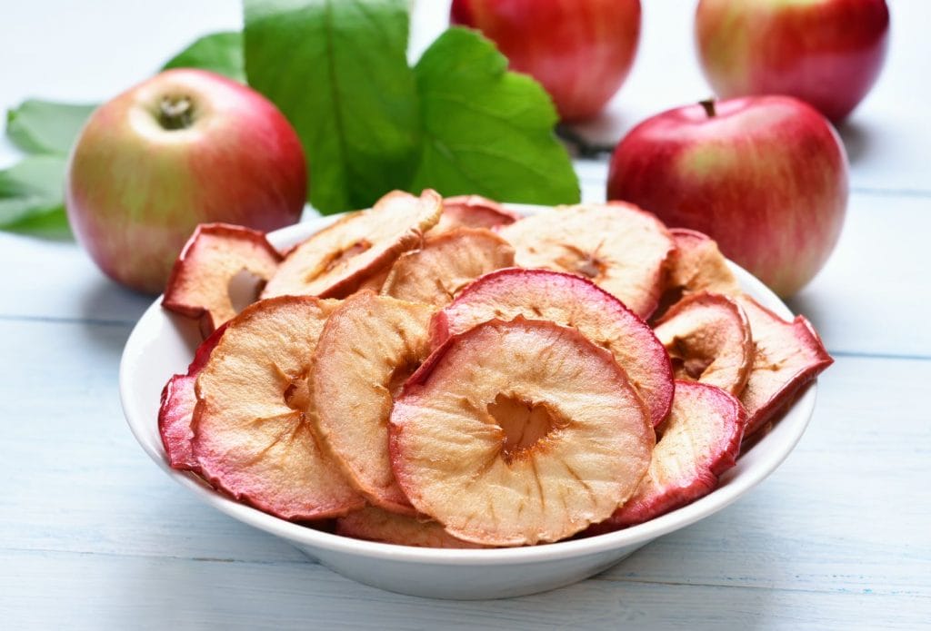 dehydrated apples in a bowl with apples around it