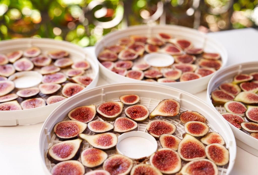 figs cut in half arranged on dehydrator trays