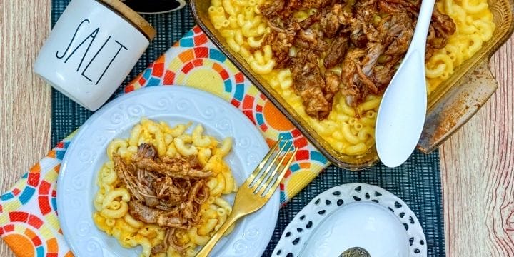 creamy mac and cheese topped with leftover pulled pork on a plate with a fork next to a dish full