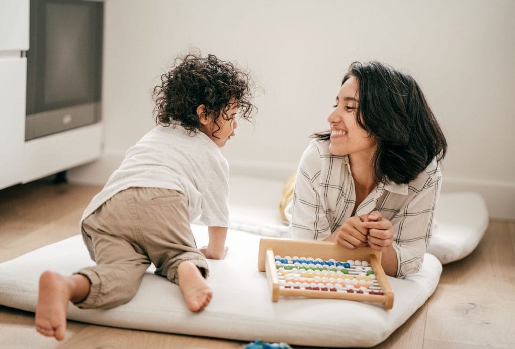 a toddler and a daycare provider playing with an abacus