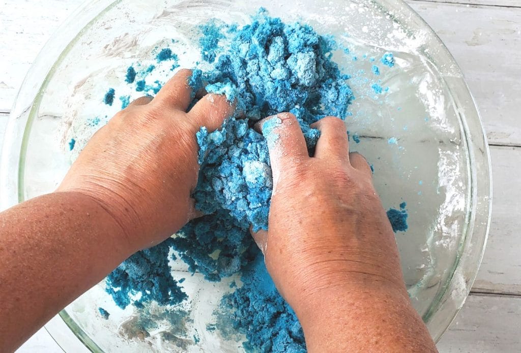 hands mixing homemade kinetic sand