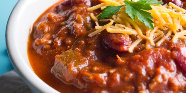 bowl of chili garnished with cheese and herbs