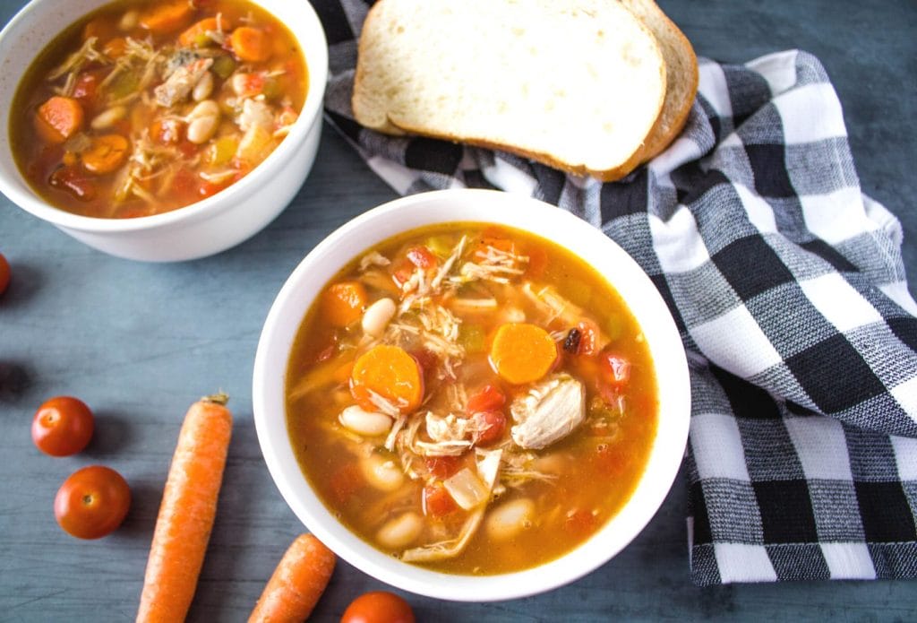 smokey pork soup from leftover pulled pork in a bowl on the table with bread and carrots