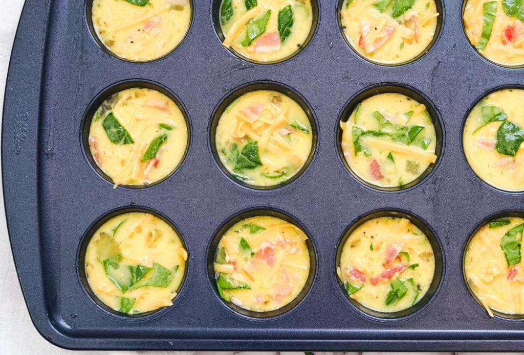 spinach and egg muffin batter in muffin tins