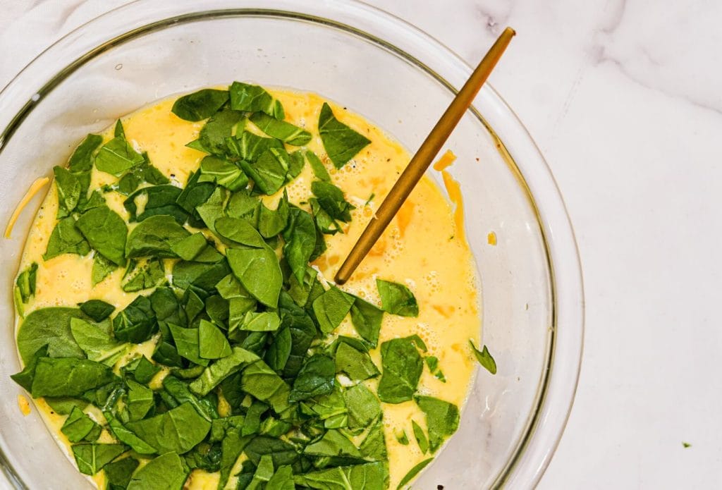 spinach egg muffins being mixed in a bowl