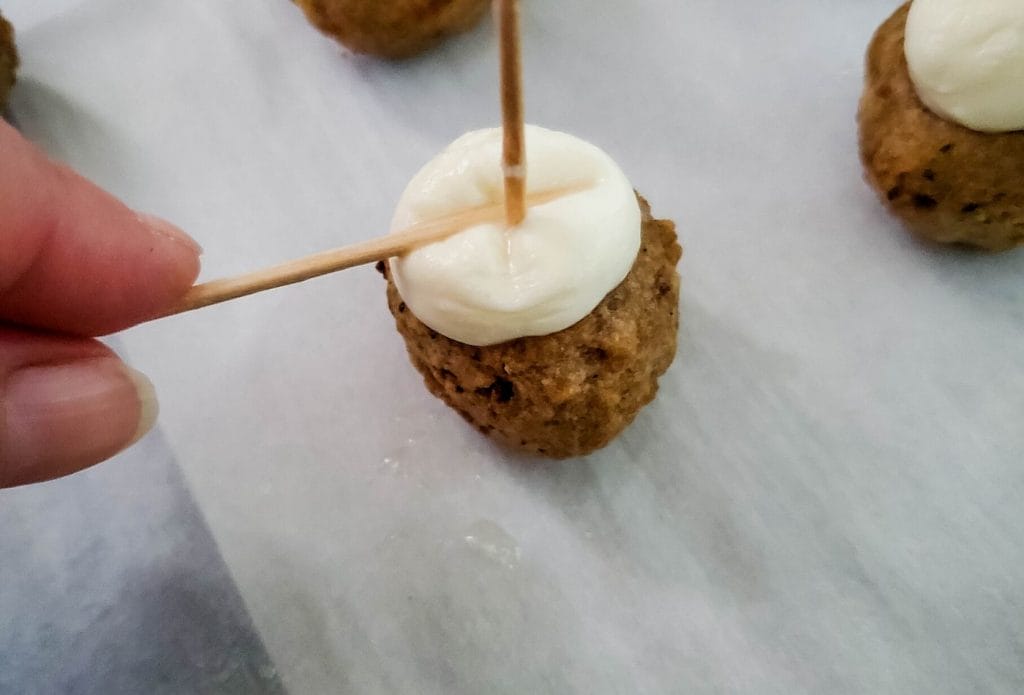 meatball with fresh mozzarella being pressed on top with a toothpick