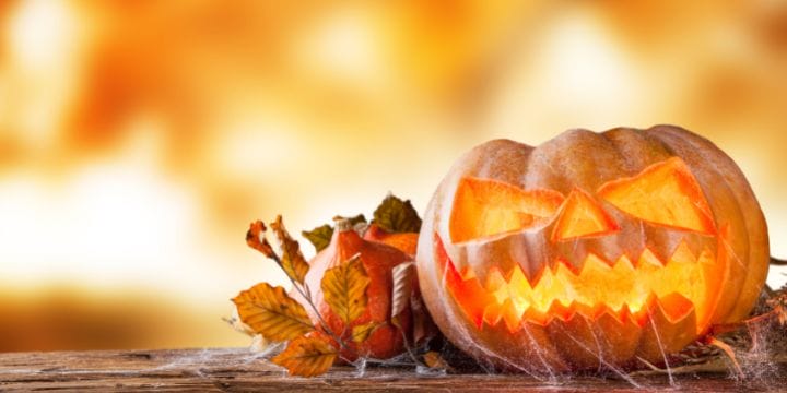 a jack o lantern with spider webs and leaves