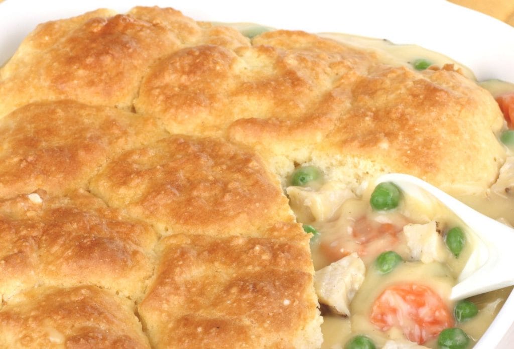 tuna pot pie topped with biscuits in a casserole dish with a serving removed
