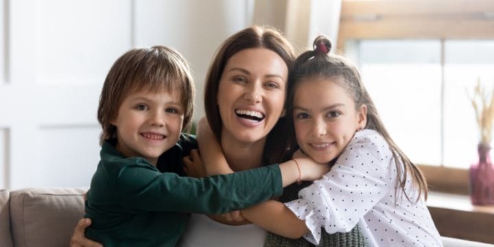 a smiling mom with two grateful kids hugging her