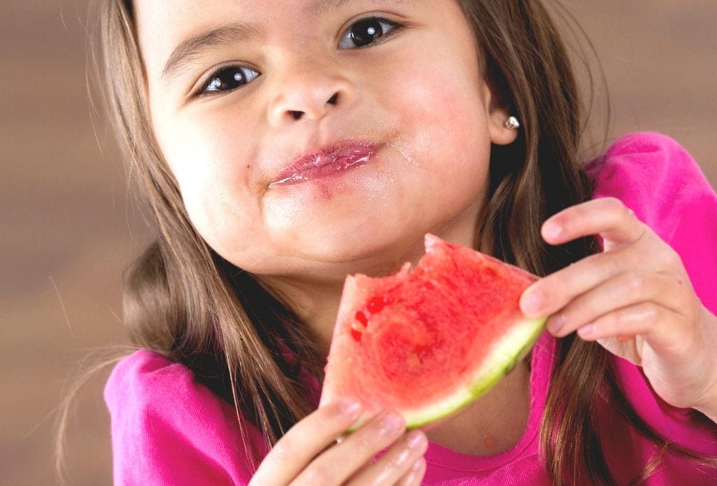 young child eating watermelon for snack